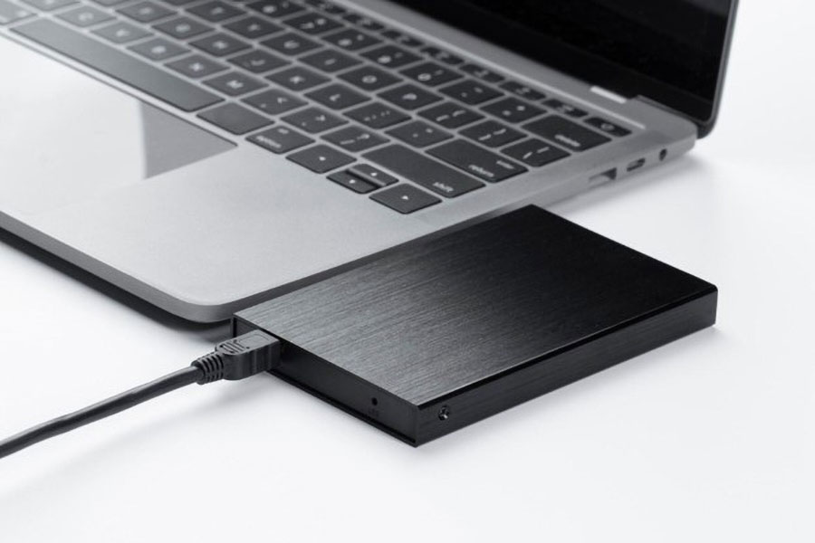 Picture of an external SSD next to a laptop.