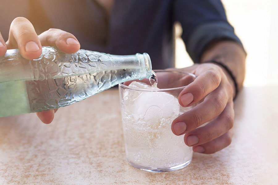 Image of a person pouring water into a glass.