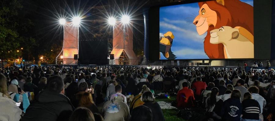 a group of people watching lion king in outdoor cinema.