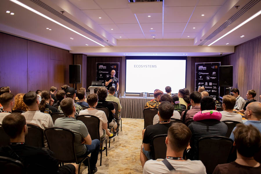 a room with a projector full of people sitting on chairs in Games Gathering Kyiv 2024.