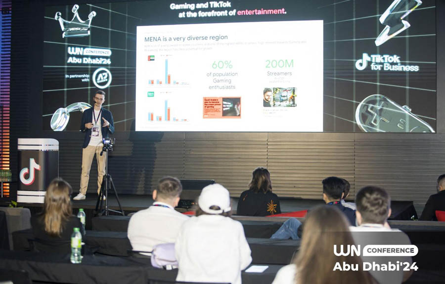 a person on a stage giving speech with a projector in nWN Conference Abu Dhabi 2025.