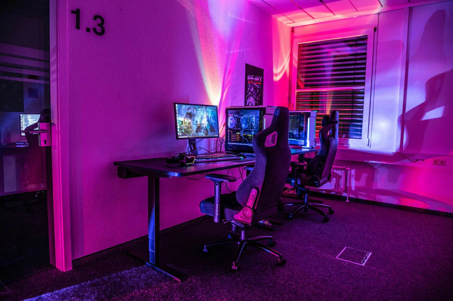 Image of a gaming room with two gaming setups on a desk.